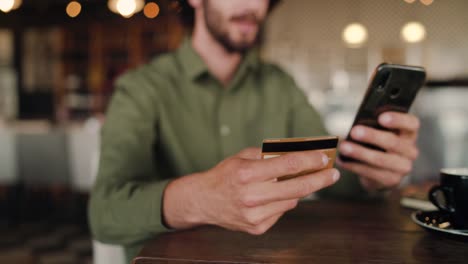 Fokus-auf-eine-Mann-Hände-tun-Online-Shopping-und-Kauf-mit-Bankkarte-beim-Entspannen-im-Café---Online-Käufe