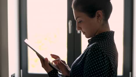 Indian-woman-holding-tablet-device-do-remote-work-standing-indoors