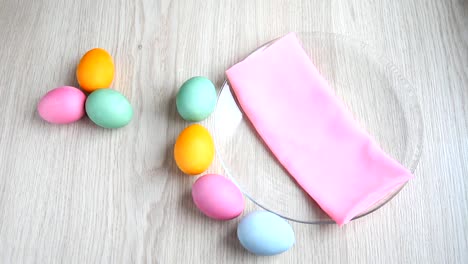 Hand-bietet-ein-Teelöffel-neben-Bunte-Eier-auf-festliche-Ostern-Tabelle.