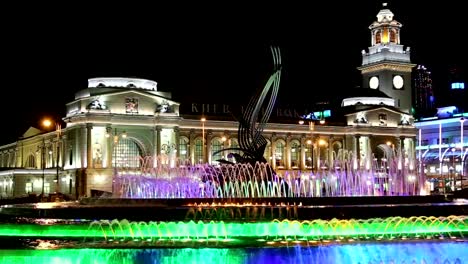 Pies-de-Europa,-animada-fuente-y-la-estación-de-ferrocarril-Kiyevskaya-iluminado-en-la-noche,-Moscú,-Rusia