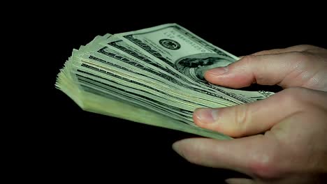 Male-Hands-Count-Hundred-Dollar-Bills-on-Black-Background