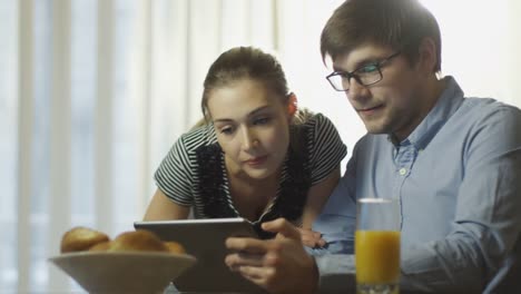 Pareja-está-leyendo-noticias-sobre-la-tableta-en-el-desayuno