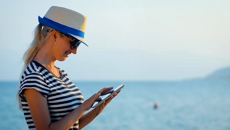 Girl-tourist-communicates-in-social-networks-on-the-tablet-in-a-trip-by-the-sea