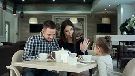 Hija-intenta-atraer-la-atención-de-sus-padres-mientras-ellos-están-ocupados-mirando-en-tableta.-Se-veía-aburrida