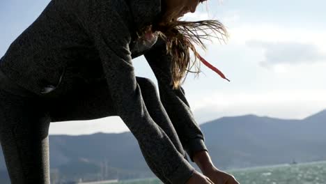 Sports-woman-getting-ready-for-run-tying-laces-of-running-shoes-on-the-beach