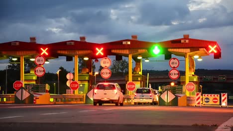 Carretera-coche-Paytoll-en-el-amanecer,-las-luces-de-noche-y-Autos-pasando-por-cabinas-de-peaje,-pagar-por-usar-la-carretera-y-autopista