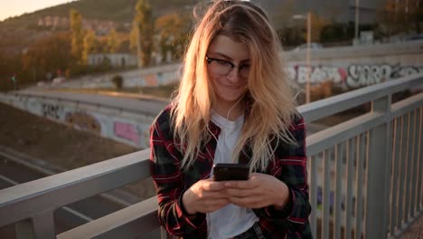 Pretty-teenager-girl-is-using-her-smartphone-at-sunset