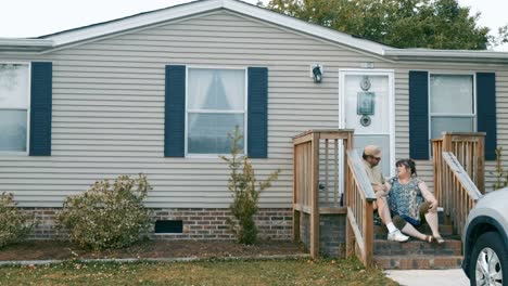 Man-and-woman-sitting-on-their-steps-of-their-manufactured-home-talking-together