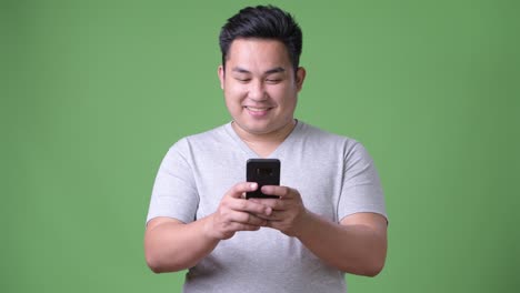 Young-handsome-overweight-Asian-man-against-green-background