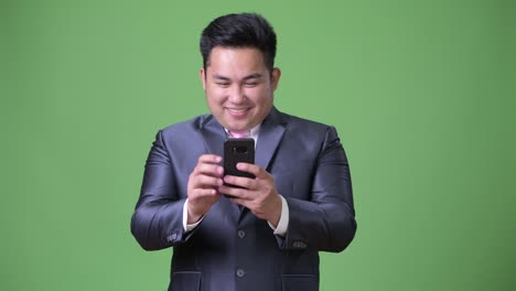 Young-handsome-overweight-Asian-businessman-against-green-background