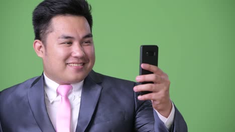 Young-handsome-overweight-Asian-businessman-against-green-background