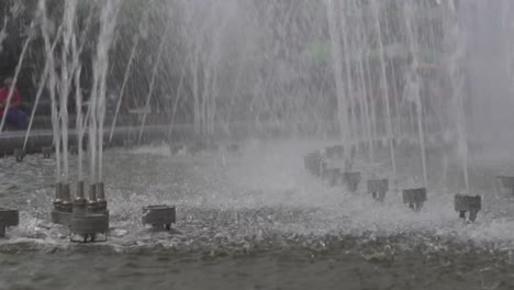 Der-Brunnen-in-der-Stadt-ist-close-up.-Wasserstrahlen-verlangsamt.-Stadtstraße-Sommer