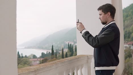 Mann-nimmt-Fotos-der-Landschaft-auf-das-Telefon,-das-er-durch-das-Fenster-sieht