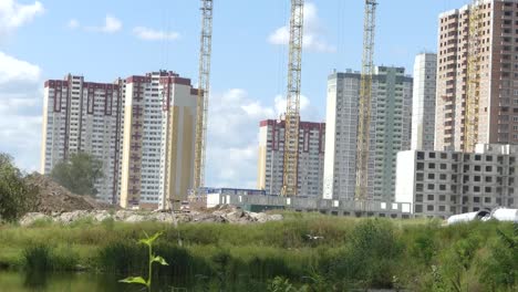 A-lake-against-the-background-of-houses-under-construction.-Skyscrapers-are-built-near-the-lake.-Construction-of-residential-buildings-near-the-lake.