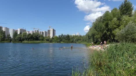 Un-lago-contra-el-fondo-de-las-casas-en-construcción.-Se-construyen-rascacielos-cerca-del-lago.-Construcción-de-edificios-residenciales-cerca-del-lago.