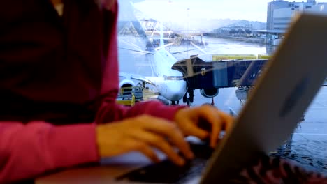 Woman-hands-is-typing-on-a-laptop-by-the-window-at-an-airport-on-the-background-of-an-airplane-close-up