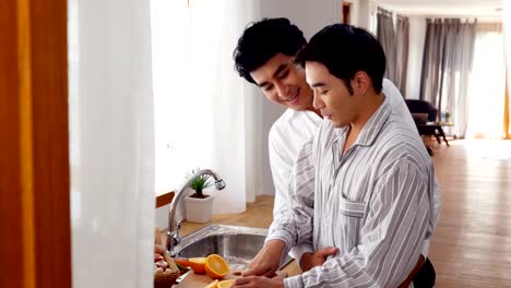 Dulce-feliz-pareja-gay-en-cocina-casera.-Hombre-que-cocina-el-desayuno-para-él-novio-con-sonrisa-atractiva.-Personas-con-gay,-homosexual,-concepto-de-relación.