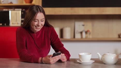 Mujer-joven-navegando-por-internet,-revisar-novedades-en-redes-sociales-durante-el-uso-de-smartphone-en-la-cocina.