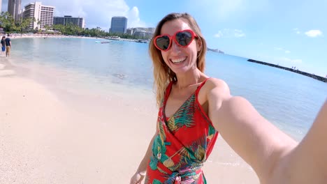 Selfie-von-Mädchen-mit-Herz-geformt-Sonnenbrille-am-Strand-von-Hawaii.-Junge-Frau,-die-eine-Selfie-am-Strand-von-Waikiki-in-Honolulu.-Hawaii-USA