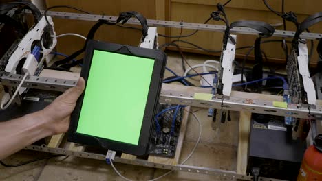 Young-trader-man-holding-tablet-with-chroma-key-green-screen-showing-ok-sign-after-checking-progress-of-cryptocurrency-mining-rig