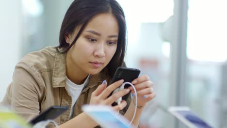 Mujer-asiática-eligiendo-modelo-de-teléfono