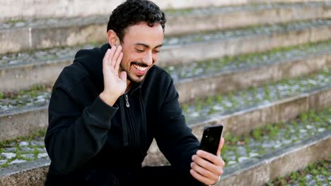 Joven-árabe-hombre-teniendo-video-chat-fuera,-agitando-la-mano