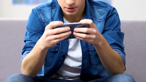 Entranced-teenager-playing-fast-paced-video-game-on-smartphone,-leisure-time