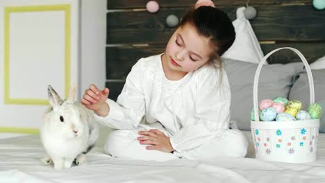 Chica-linda-divirtiéndose-con-conejo-en-la-mañana-de-Pascua