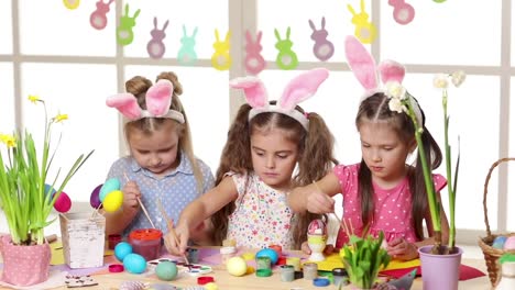 Niños-felices-usando-orejas-de-conejo-pintando-huevos-el-día-de-Pascua.