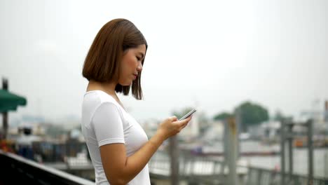 Jovencita-asiática-hablando-por-teléfono-al-aire-libre-al-lado-del-río.