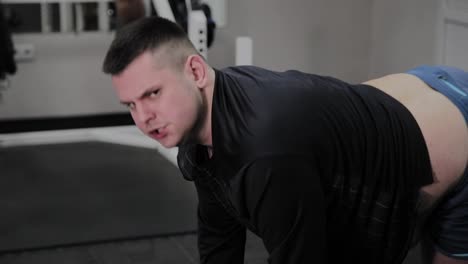 Cheerful-fat-man-performs-a-wrong-exercise-in-the-gym.-For-the-first-time-in-a-fitness-club