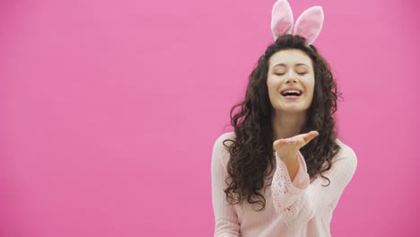 Beautiful-young-girl-standing-on-a-pink-background.-During-this,-there-are-ears-of-rabbits-on-the-head.