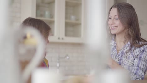 Young-mother-and-her-preteen-daughter-talking-on-the-kitchen.