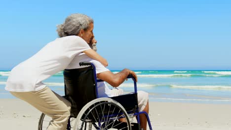 Side-view-of-active-senior-African-American-woman-embracing-disabled-senior-man-on-the-beach-4k