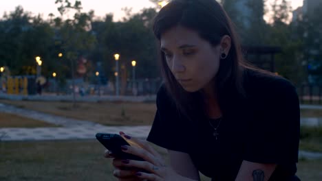 Mujer-joven-con-teléfono-inteligente-en-el-parque