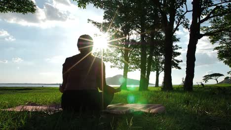 Asiatische-Frauen,-die-Yoga-praktizieren,-entspannen-in-der-Natur-im-Abendsonnenschein,-Lotus-posieren-auf-Meditationssitzung.-Fitness-und-gesundes-Lifestyle-Konzept.