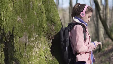 Caucasian-girl-in-the-forest-with-a-mobile-phone.-Young-tourist-on-vacation-in-the-forest