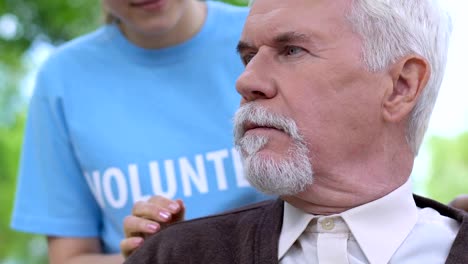 Gracious-volunteer-talking-to-disabled-old-man-in-wheelchair-during-park-walk