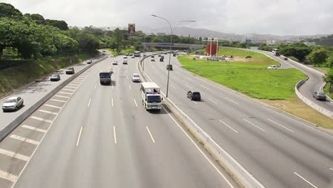 Many-cars-and-trucks-driving-on-road-in-a-large-modern-urban-city-area