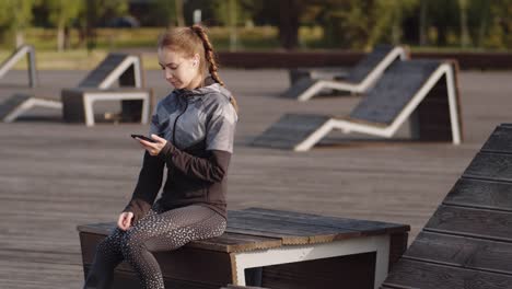 Sportlerin-mit-Telefon-im-Park