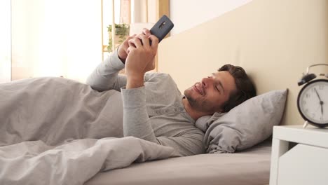 Man-using-mobile-phone-in-bed