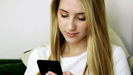 Young-smiling-woman-using-smartphone,-texting-on-mobile-phone-in-modern-cafe.-4K