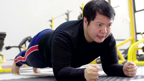 Asian-man-trying-to-exercise-with-dumbbell-in-fitness-gym,-Healthy-lifestyle,-weight-loss-desire