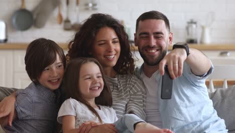 Happy-parents-with-kids-laughing-using-smart-phone-at-home