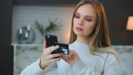 A-woman-holds-a-credit-card-and-a-smartphone-pressing-on-the-touchscreen-screen.-Online-shopping-for-Christmas.-Pay-for-delivery-of-goods