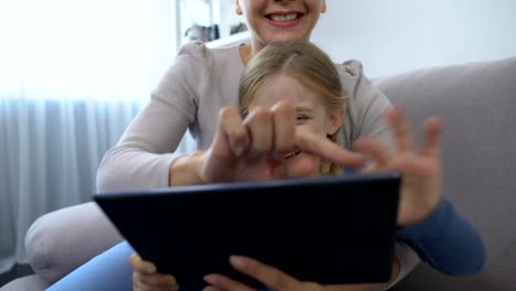 Joyful-cute-girl-and-mother-touching-tablet-screen-and-smiling-playing-game,-fun