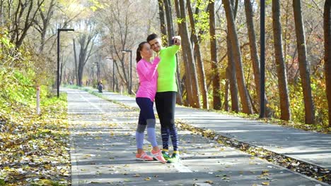 Loving-couple-of-athletes-posing-for-selfie-photo-in-autumn-park