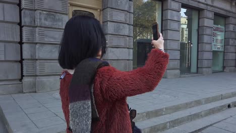 Mujer-asiática-tomando-fotos-por-la-cámara-del-teléfono-móvil-en-la-calle-Europa