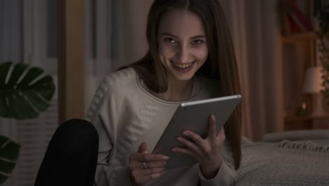 Teen-girl-having-fun-using-digital-tablet-at-night