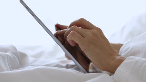 Young-woman-using-digital-computer-tablet-after-waking-up.